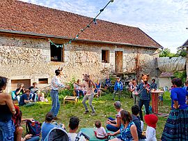 Trois personnes portent des têtes d'animaux et jouent de la musique. Ils sont entourés par le public.